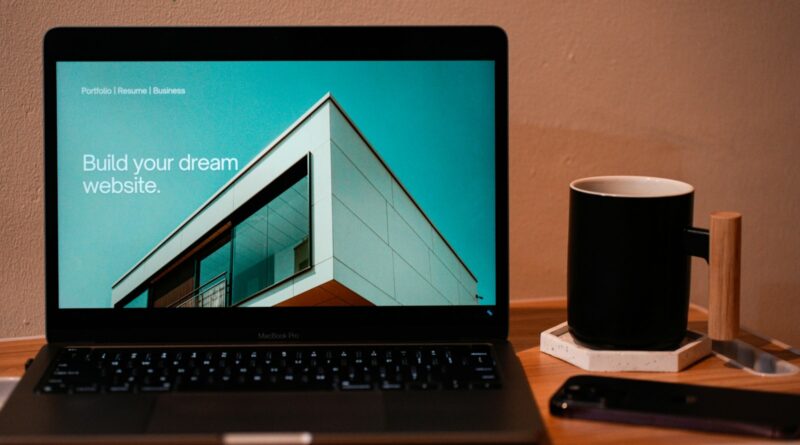 Laptop on a wooden desk with a mug beside it, ready for website work