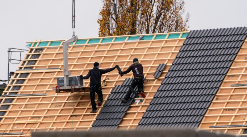 Workers installing roof tiles on a new building, showing how roof components fit together